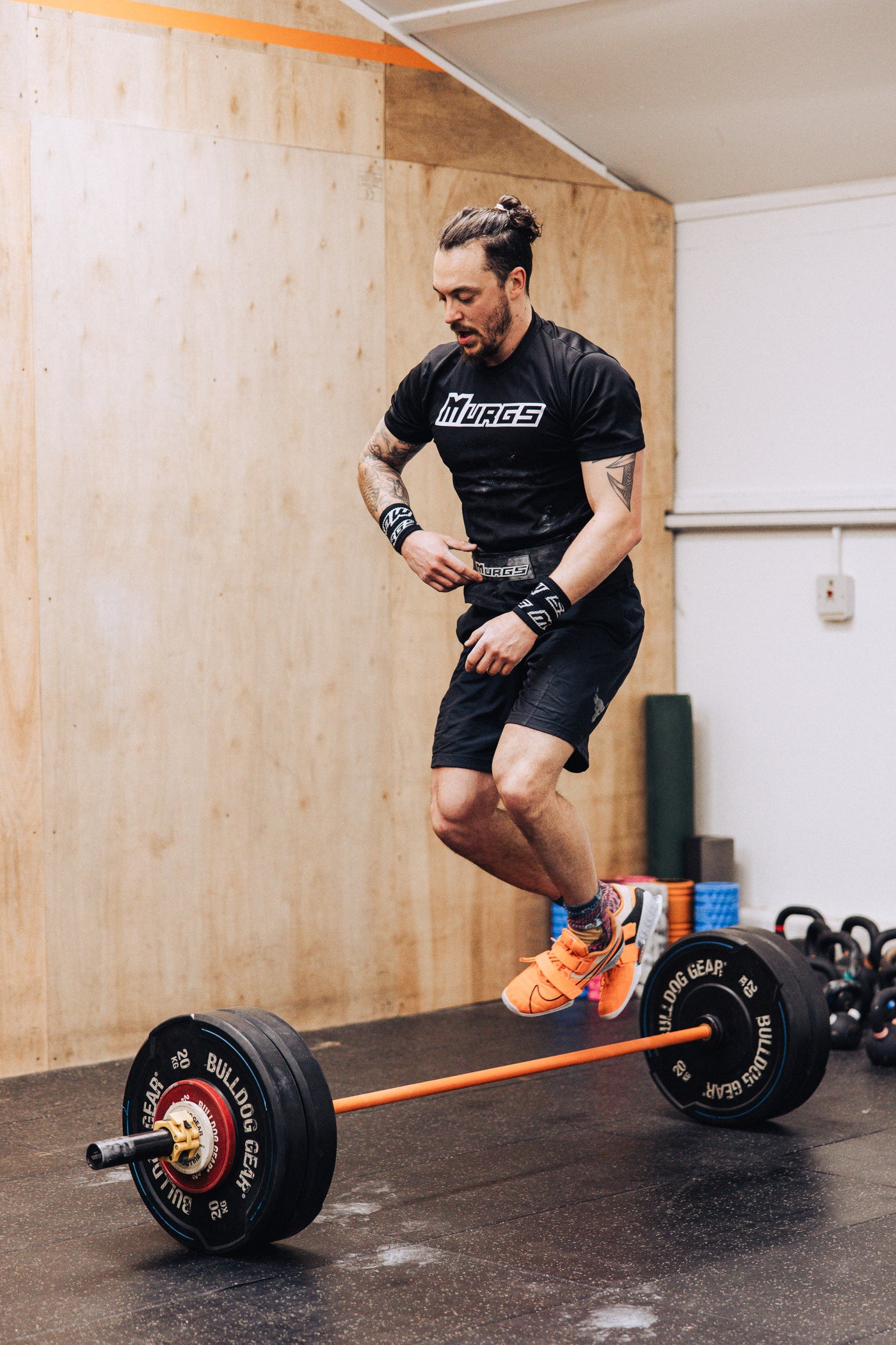 A detailed showcase of CrossFit workout attires designed for success. On one side, there's a Caucasian man in his late-20s, a pair of breathable, athletic shorts, a sweat-absorbent t-shirt, and the pe