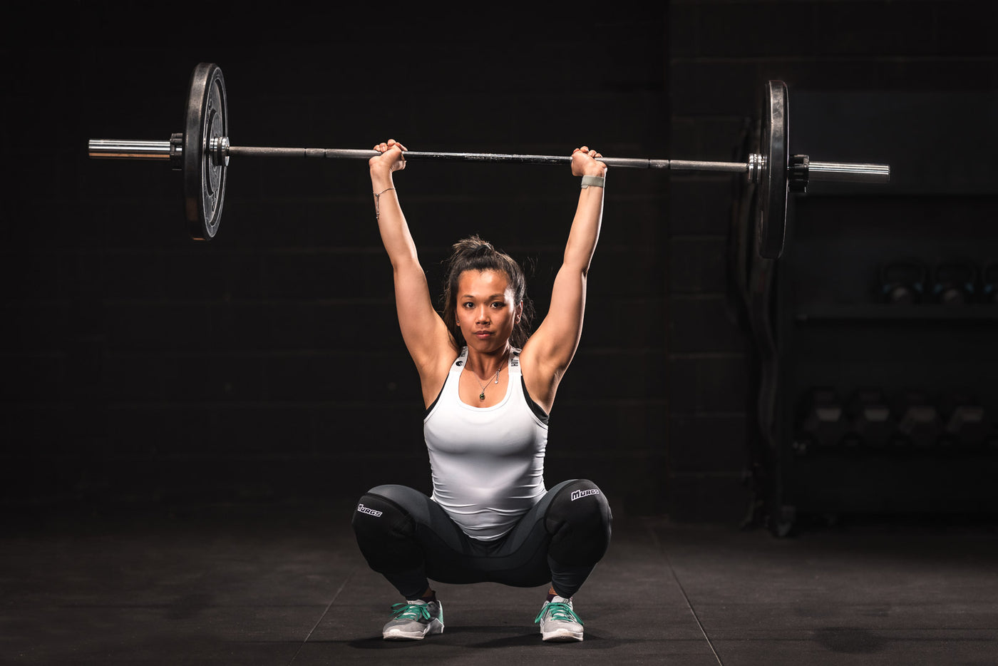 Illustrate a gym scene showcasing five techniques that can enhance CrossFit performance. 1) A Hispanic woman demonstrating the correct form of a kettlebell swing. 2) A Caucasian man showing optimal bo